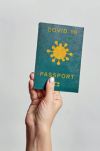 Trzymana w dłoni mała książeczka podpisana Covid-19 Passport.